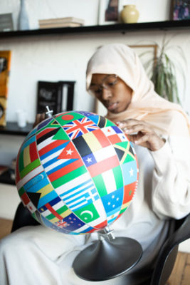 Woman with globe c covered in international flags